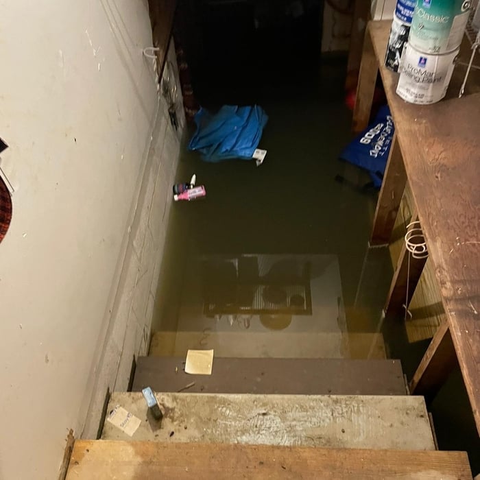 Flooded basement or room with standing water, scattered items, and blue cloth